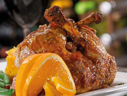 Duck confit served with citrus compote and green salad on a rustic plate