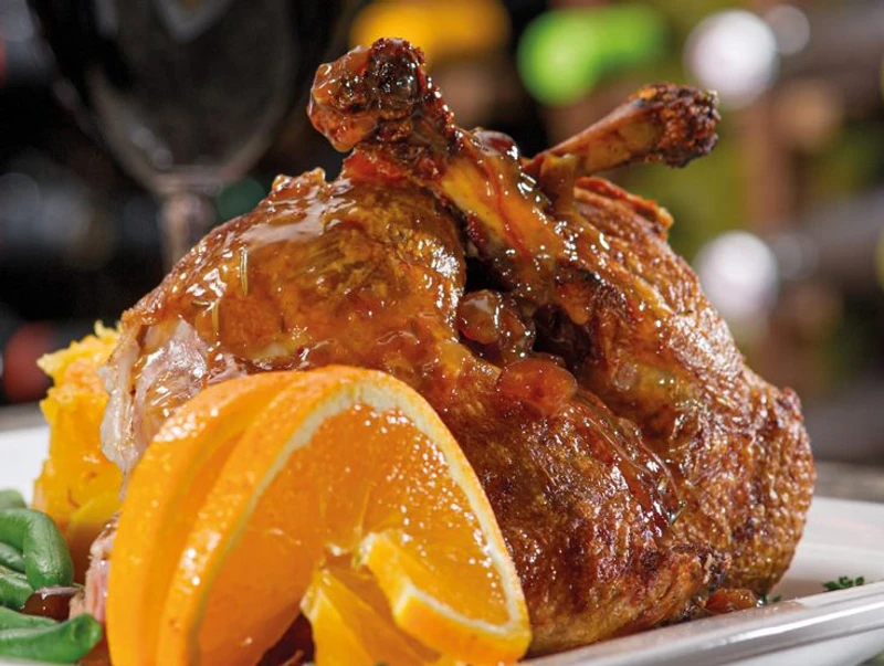 Duck confit served with citrus compote and green salad on a rustic plate