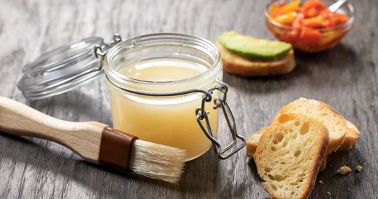 A selection of fats including duck fat, butter, olive oil, and coconut oil on a rustic wooden board