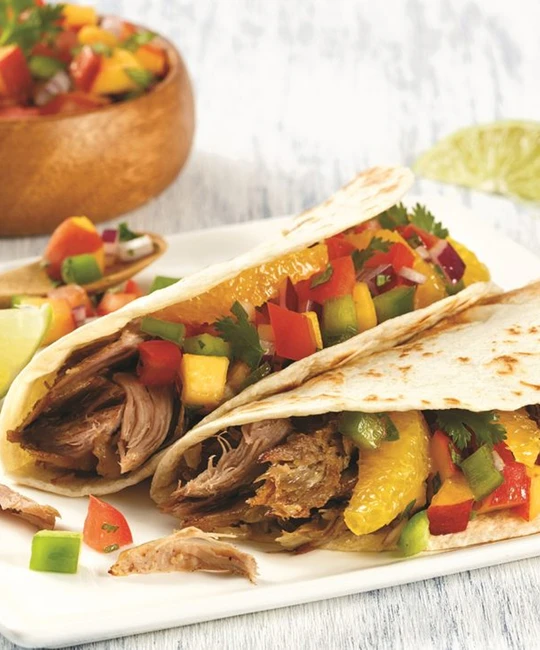 Pulled duck tacos with orange segments and herbs