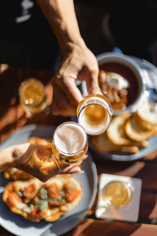 Glasses of wine and small bites on a wooden table in warm afternoon light
