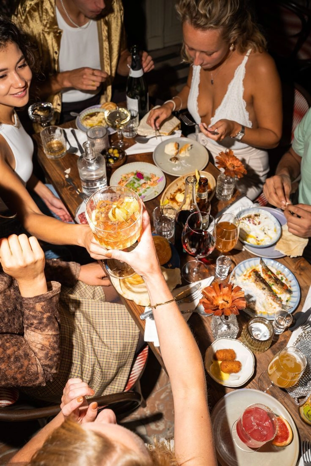 Friends sharing a rustic meal outdoors with wine, bread, and duck confit