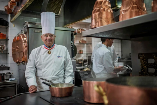 Artisan preparing duck confit by hand in a rustic kitchen